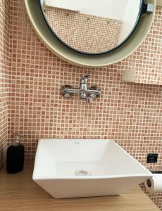 um lavatório branco na casa de banho com um espelho em Cosy studio overlooking Porto Germeno gulf em Aigósthena