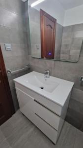 ein Badezimmer mit einem weißen Waschbecken und einem Spiegel in der Unterkunft VibesCoruña- San Rosendo 25 in A Coruña