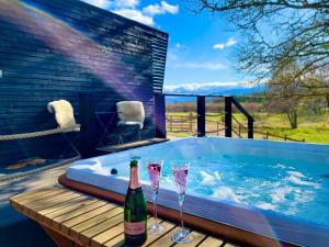 a hot tub with two glasses and a bottle of champagne at The Roost in Aviemore