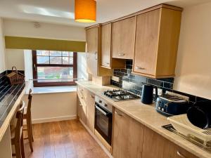 a kitchen with wooden cabinets and a stove top oven at Apartment in Coldstream in Coldstream