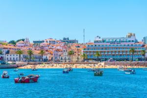 a group of boats in the water near a beach at Hotel Baia in Cascais