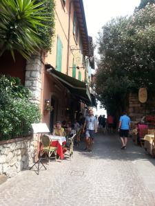 un grupo de personas caminando por una calle con mesas y sillas en Appartamenti Corneliani, en Sirmione