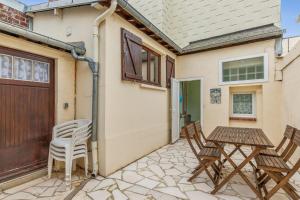 un patio avec des chaises et une table devant une maison dans l'établissement Maison Flatelle - Welkeys, à Trouville-sur-Mer