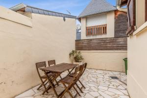 une table et des chaises en bois sur une terrasse dans l'établissement Maison Flatelle - Welkeys, à Trouville-sur-Mer