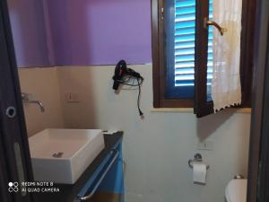 bagno con lavandino bianco e finestra di Turismo Egadi - Villette a Favignana