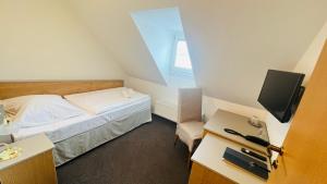 1 dormitorio pequeño con 1 cama y TV en Hotel PAYER en Teplice