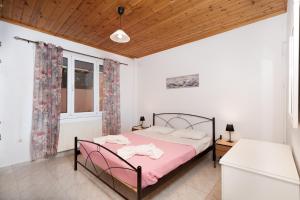 a bedroom with a bed with pink sheets and a window at MTC-D Apartments by the Sea and Airport in Porto Rafti