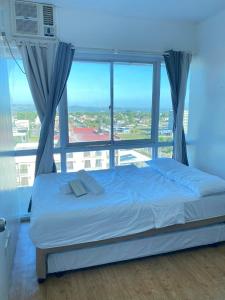 Bett in einem Zimmer mit einem großen Fenster in der Unterkunft SK's Crib - Fully Furnished Condo @ Primavera Apts in Cagayan de Oro