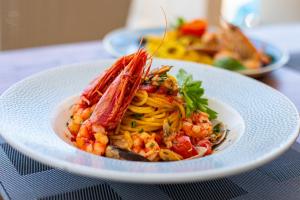 a plate of pasta with shrimp and vegetables on a table at Hotel Riva Del Sole in Cefalù