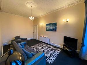 a living room with a couch and a tv at Paisley Pad: Glasgow Gateway in Paisley