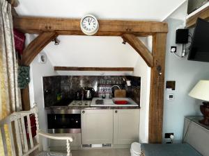 una cucina con piano cottura e orologio a muro di Remarkable 1-Bed Cottage near Henley-on-Thames a Henley on Thames