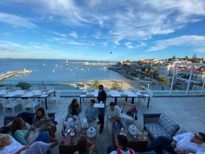 a group of people sitting on a deck with a view of the water at Hotel Baia in Cascais