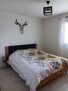 a bedroom with a bed with a bedspread with a deer on the wall at Villa Côté Ceüze Pelleautier in Pelleautier