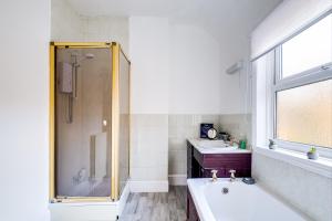 a bathroom with a shower and a tub and a sink at Lovely Central Loughborough Abode - Games Room in Loughborough