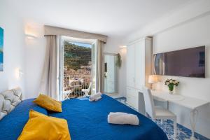 a bedroom with a blue bed with a desk and a window at Casa Diodora, Costiera Amalfitana in Maiori