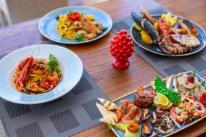 four plates of food on a wooden table at Hotel Riva Del Sole in Cefalù