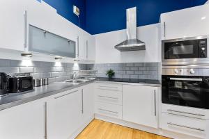a white kitchen with a sink and a microwave at Spacious Contemporary 2 bed flat, Central London in London