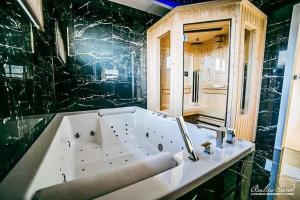 a bath tub in a bathroom with a black wall at Luksusowe Apartamenty Baltic-Sand in Słajszewo