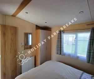 1 dormitorio con 1 cama junto a una ventana en Spacious 2 bed @ Seal Bay (was Bunn Leisure), en Selsey