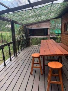 una mesa de madera y 2 taburetes en una terraza de madera en Cabaña Campestre Miramar, en Playa Verde