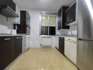 una cocina con armarios negros y electrodomésticos blancos en Amplio apartamento con 2 baños en Logroño