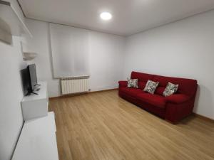 a living room with a red couch and a tv at Amplio apartamento con 2 baños in Logroño +1 photo