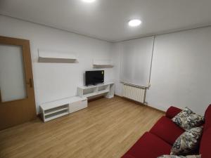 a living room with a red couch and a flat screen tv at Amplio apartamento con 2 baños in Logroño