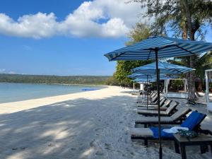 a row of chairs and umbrellas on a beach at SCARLET SAILS VILLA in Koh Rong Island