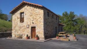 un pequeño edificio de piedra con una puerta en un aparcamiento en Casa Rural Los Riveros de Jeromo en Selaya