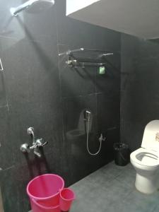 bagno nero con servizi igienici e doccia. di Ruthran Guest House a Mamallapuram