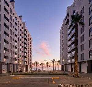 un rendu de deux grands immeubles avec un palmier dans l'établissement Expoholidays - Primera línea de playa Villapepita PARKING gratis, à Almería