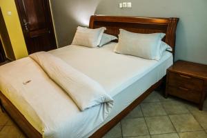 - un lit avec des draps et des oreillers blancs dans l'établissement Residence Le Carat, à Douala