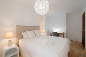 um quarto com uma cama branca e um lustre em For You Rentals Central Apartment Atocha Station Madrid TEL3 em Madri