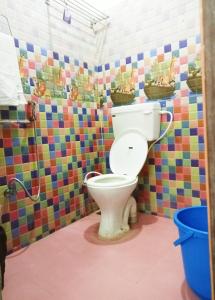 a bathroom with a toilet in a colorful tiled wall at Ruthran Guest House in Mahabalipuram