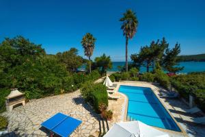 una piscina con due ombrelloni e l'acqua di Avlaki Beach House,stylish villa in Kassiopi a Kassiopi