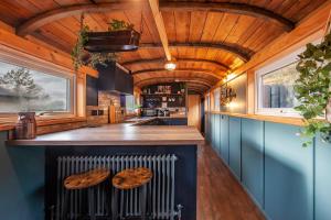 una cocina con armarios azules y un bar con taburetes de madera en The Carriage at Creagan, en Creagan