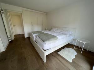 a bedroom with a white bed and a stool at Casa Segnale in Ascona