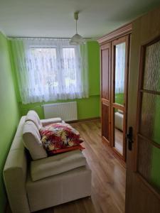 a green room with a couch and a window at Apartament blisko Świeradowa in Mirsk