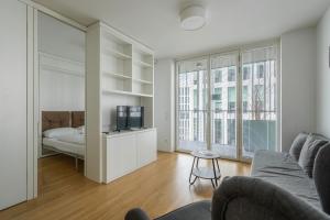 a living room with a couch and a bed and windows at easy flat Green Prater in Vienna