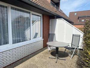 2 sillas y una mesa frente a una ventana en Apartmenthaus am Watt Büsum, en Büsum