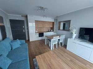 a living room with a blue couch and a table at Apartament Sarbinowo in Sarbinowo