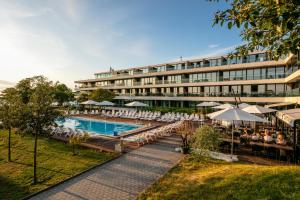 a hotel with a pool and tables and chairs at NOVI Resort in Visby
