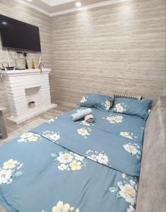 un letto con un piumone blu e fiori sopra di Комфортный дом до 4х человек. Есть парковка на 2 машины, Wi-Fi, TV. a Bishkek