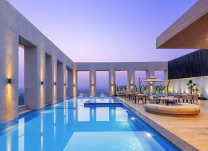- une piscine dans un hôtel avec des tables et des chaises dans l'établissement Bellevue Sarovar Premiere Junagadh, à Junagadh