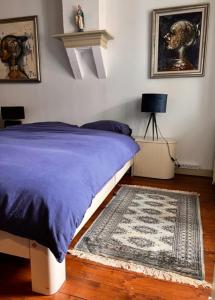 een slaapkamer met een bed met een blauwe deken en een tapijt bij Het Kasteeltje in Vlissingen