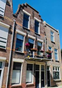 een bakstenen gebouw met ramen en bloemen op het balkon bij Het Kasteeltje in Vlissingen