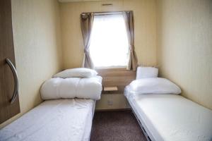 Tempat tidur dalam kamar di Lovely 8 Berth Caravan Nearby Scratby Beach At California Cliffs Park 50071d
