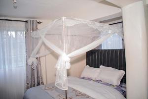 ein weißes Himmelbett mit weißer Bettwäsche und Kissen in der Unterkunft Zuriel Homes 1 Bedroom apartment in Kakamega