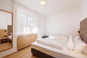 biała sypialnia z łóżkiem i lustrem w obiekcie Ferienhaus Törggelehof w mieście Tscherms