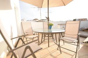 una mesa y sillas con una sombrilla en el balcón en NORAY Home, en Barbate